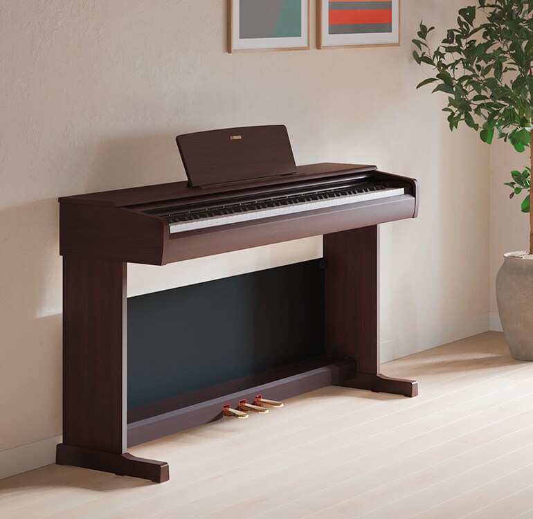 A living room featuring an ARIUS piano with houseplants and a sofa, harmoniously integrated with the interior