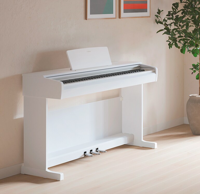A living room featuring a white  ARIUS piano with houseplants and a sofa, harmoniously integrated with the interior