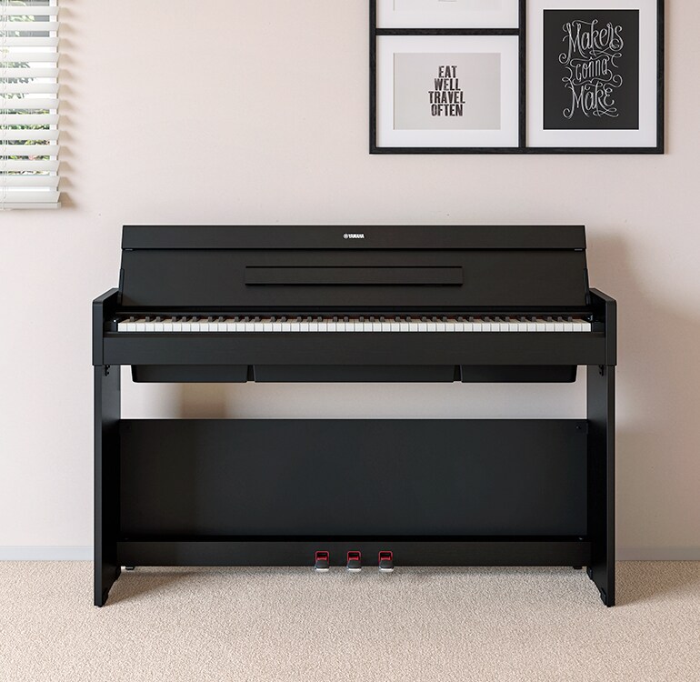 A living room featuring a black ARIUS piano placed next to wall shelves on which lamps and a diffuser are placed, hamoniously  integrated with the interior.