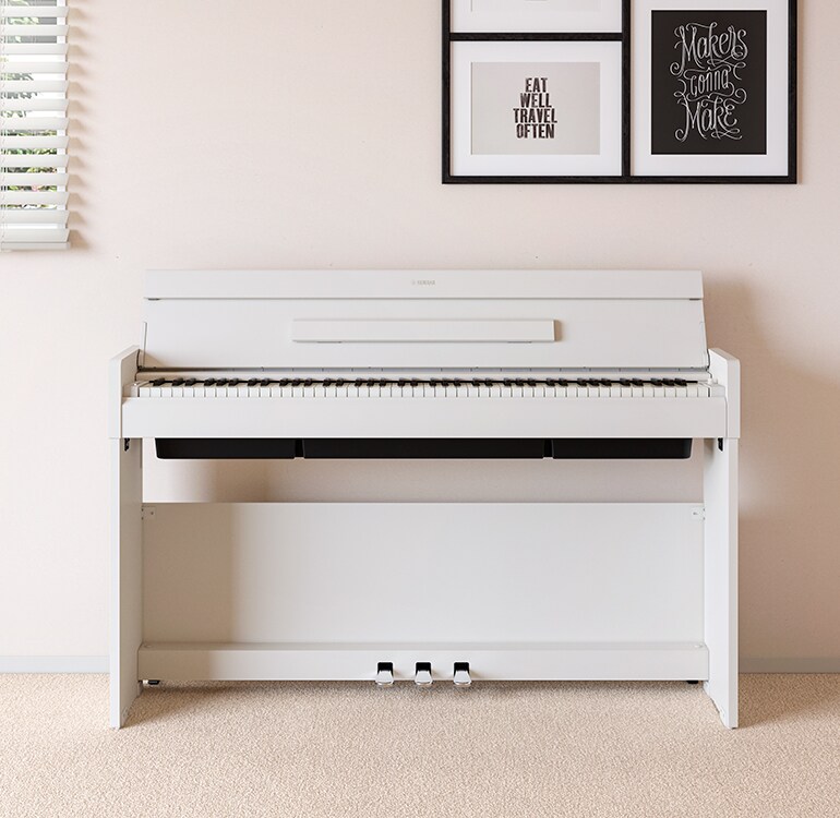 A living room featuring a white ARIUS piano placed next to wall shelves on which lamps and a diffuser are placed, hamoniously  integrated with the interior.